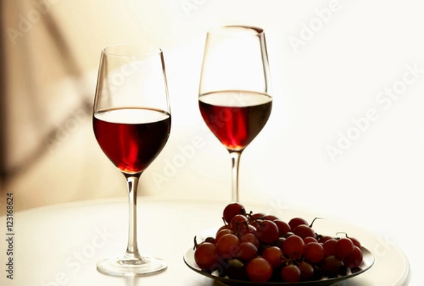 Fototapeta Glasses with red wine and grape on white table