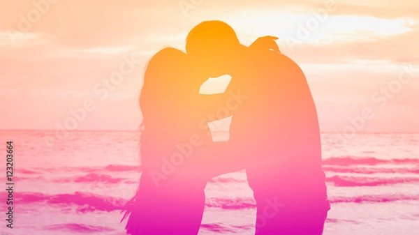 Fototapeta Silhouette couple kissing in pink tone on the beach with heart bokeh for valentines theme.