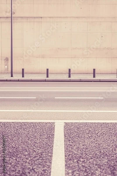 Fototapeta Empty road with tall concrete wall in background Minimalist urban scene
