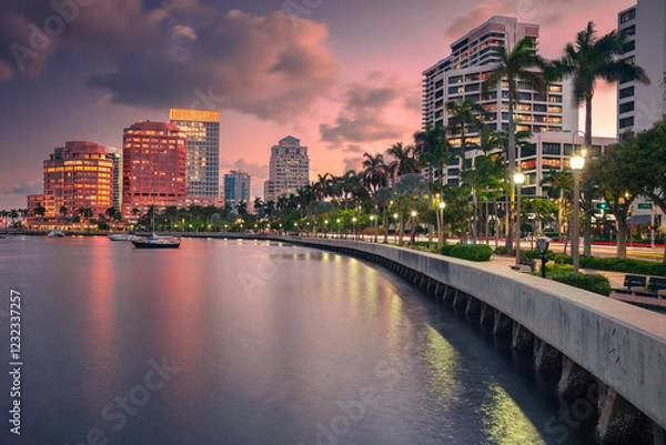 Obraz West Palm Beach, Florida, USA. Skyline of West Palm Beach, Florida, at dusk. Tall buildings with reflective glass facades line the waterfront, casting colorful reflections on the water. 