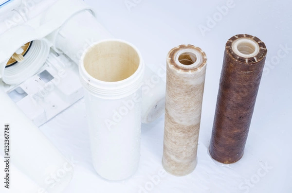 Fototapeta Dirty used set of filter cartridges of a three-stage water filter with a coating of metal impurities on a white background