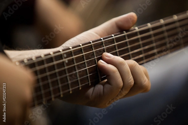 Fototapeta Musician's fingers on the strings of a guitar closeup