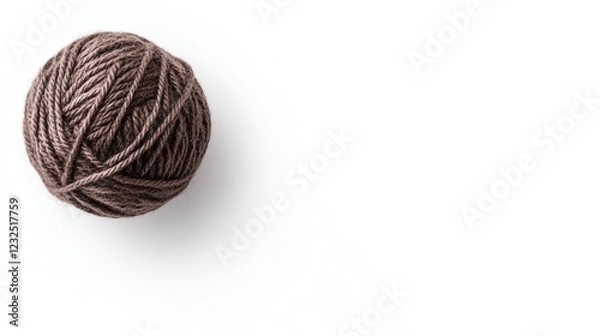 Fototapeta A soft, brown ball of yarn resting on a white surface, perfect for knitting or crafting projects.