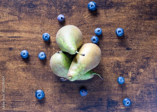 Fototapeta A bunch of pears and blueberries on a wooden table. The pears are green and the blueberries are blue