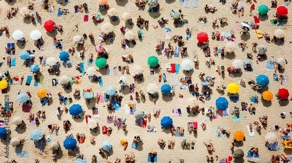 Fototapeta Aerial view of a crowded beach with people sunbathing and colorful umbrellas on sand