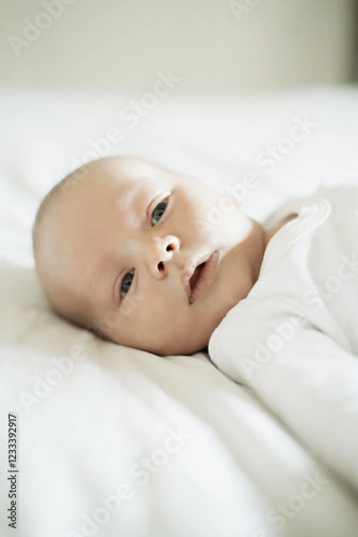 Fototapeta Baby, nursery and young newborn on a home bedroom in the morning calm and relax. Healthy boy, small child face and a house with a toddler ready for a nap, sleeping and rest on a duvet and blanket