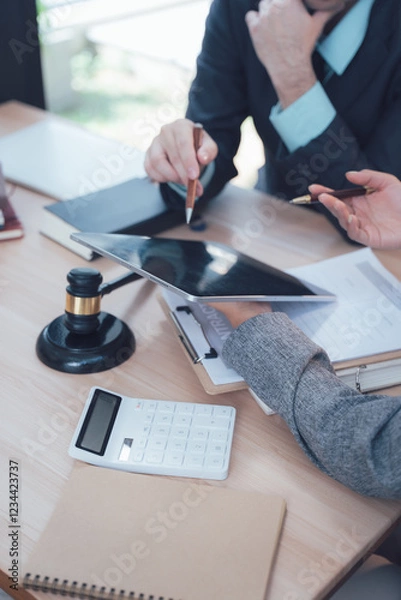 Fototapeta Legal Collaboration: Two business professionals engaged in a serious conversation while reviewing documents and utilizing a tablet,  focused on achieving a legal resolution.