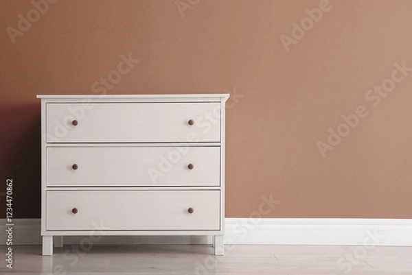 Fototapeta Wooden chest of drawers near wall in shade of mocha mousse. Stylish interior with trendy color of 2025 year
