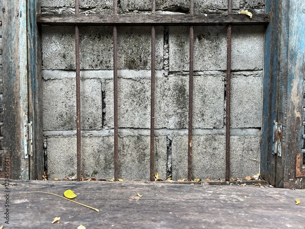 Fototapeta Old wooden window with metal bars and concrete wall