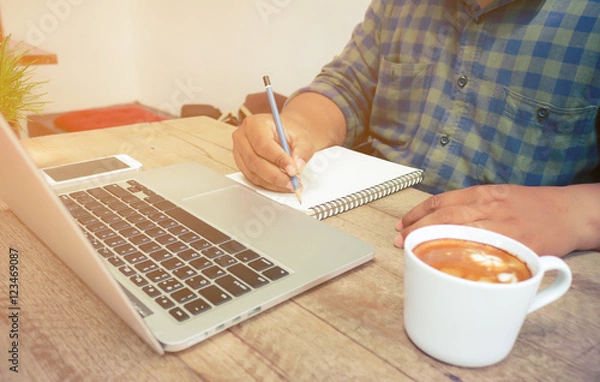 Obraz Man write on notebook with laptop and coffee cup vintage tone.