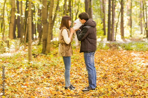 Fototapeta Happy and young family relaxing together in golden and colorful autum nature.