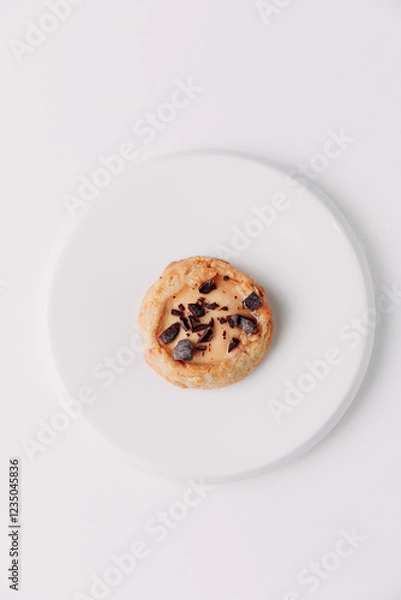 Fototapeta Round cookie with chocolate crumbs on a white plate against a white background