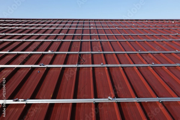 Fototapeta Aluminum Mounting Structures Being Installed on a Red Metal Roof for Future Solar Panels