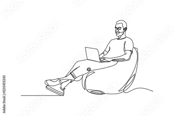 Fototapeta Relaxed Man Working from Home on Laptop in Beanbag Chair