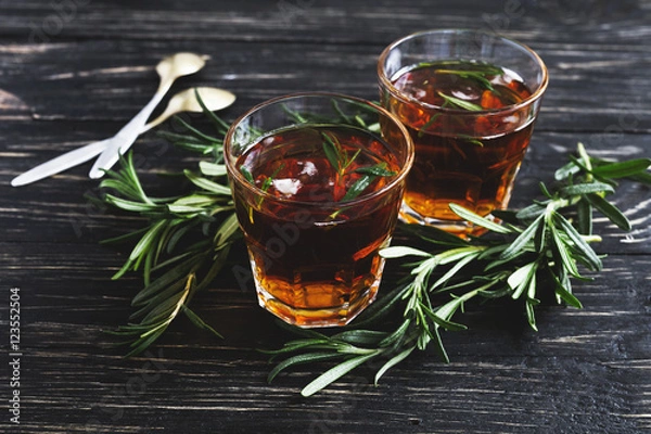Fototapeta Cold rosemary tea with ice on wooden table