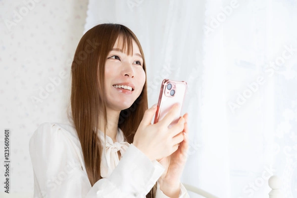 Fototapeta 部屋でスマートフォンを持っている若い女性