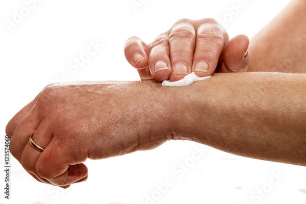 Obraz senior woman rubbing her wrist with a pain relieving cream