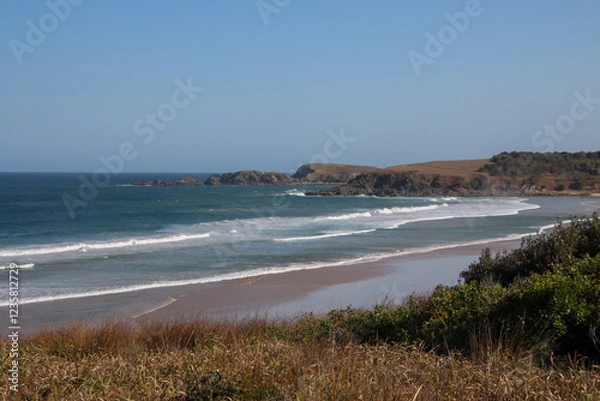 Obraz A scenic coastal landscape with rolling waves breaking on a sandy beach