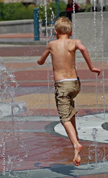 Fototapeta boy running and jumping through a fountain