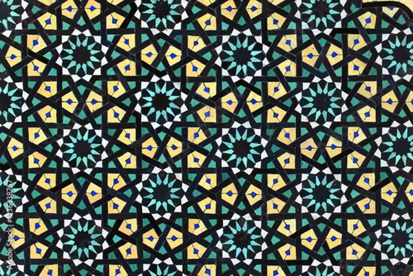 Fototapeta A detailed Islamic geometric mosaic featuring vibrant colors and symmetrical patterns. The design showcases traditional arabesque motifs with star shapes and interwoven lines