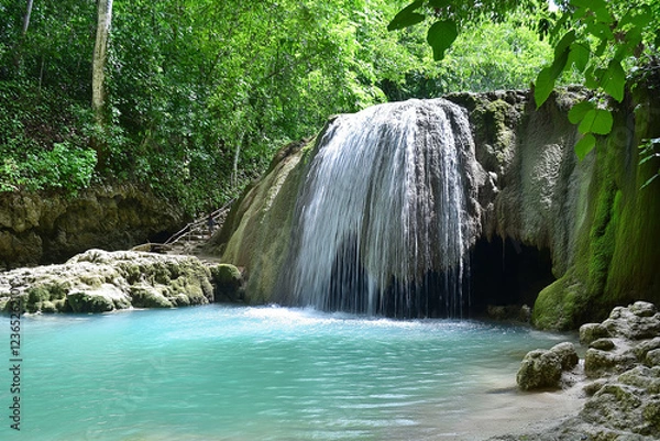 Obraz A hidden waterfall deep in the jungle, surrounded by lush green moss