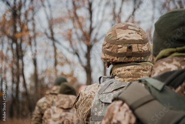 Fototapeta Military Personnel Walking on Rural Road. A group of military men returning after completing a task. Soldiers in military uniform walk on through the forest with their backs to the cell. 
