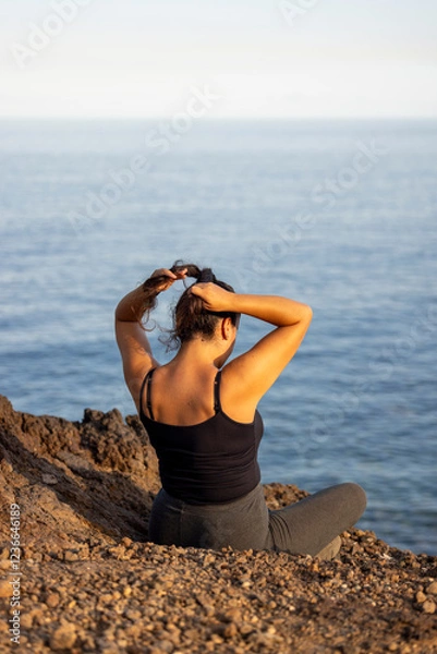 Obraz Chica arreglando el pelo en un acantilado sobre el mar