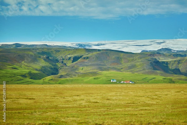 Fototapeta Beautiful nature landscape with green fields and majestic cliffs with ice and snow in Southern Iceland.