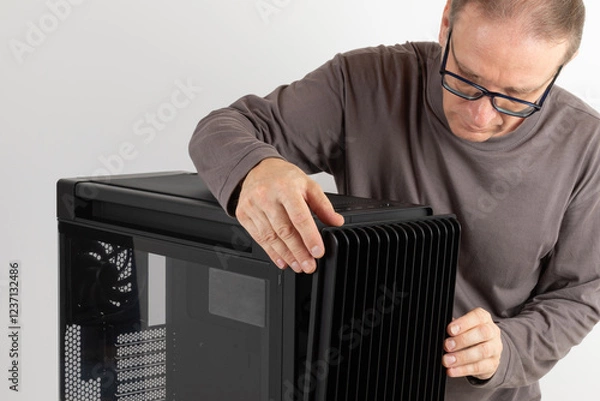 Fototapeta  Man removing  15.5 mm front panel grille with 45% porosity with dust filter from  PC case, empty big tower, chassis, on side is tempered-glass.