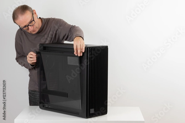 Fototapeta Man removing  tempered-glass left panel from  PC case, empty big tower, chassis.