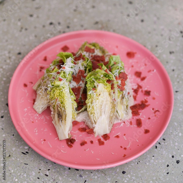 Fototapeta Cesar Salad. Top view of Romain Lettuce and bacon crisp topping for Cesar Salad served in a pink dish.