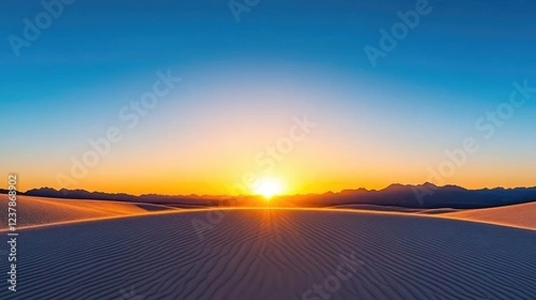 Fototapeta Sunrise over a vast desert landscape with rippling sand dunes and distant mountains