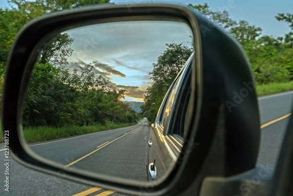 Fototapeta  Reflection seen through car side mirror -  two-lane winding road with twilight sky and sunset
