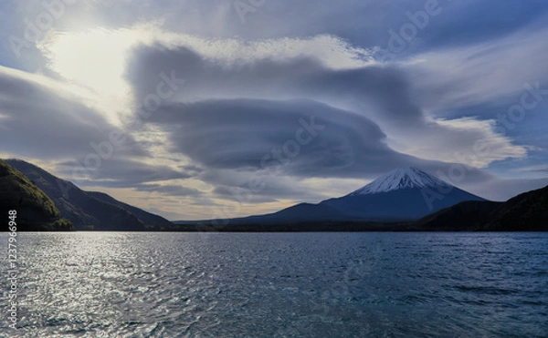 Obraz Morning view of a snow-capped Mount Fuji from the north shore of Lake Motosu, with a unique circular cloud formation partially blocking the sun