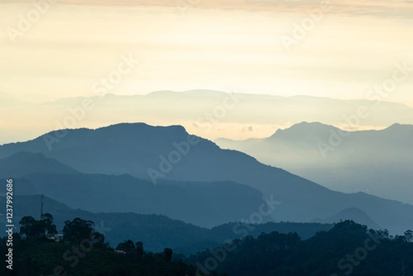 Fototapeta Kodaikanal offers breathtaking views at dawn, with soft light enhancing the peaks and valleys. Gentle mist cloaks the distant mountains, creating a tranquil atmosphere.