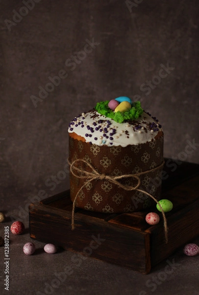 Fototapeta Easter cupcake with icing on wooden box on dark background with colored eggs