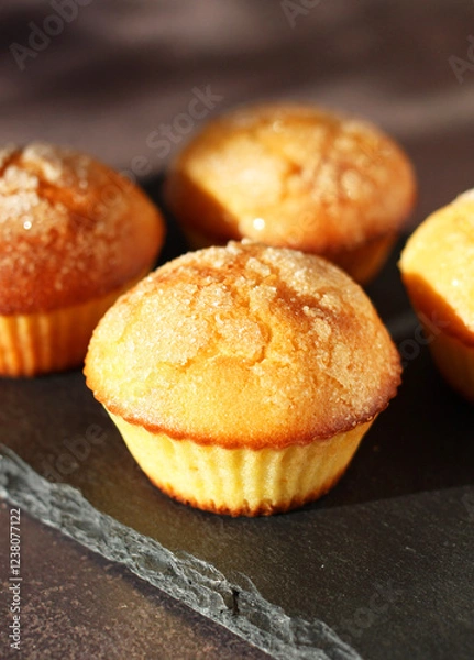 Fototapeta Dessert muffins with sugar crust on a black stand on a dark background