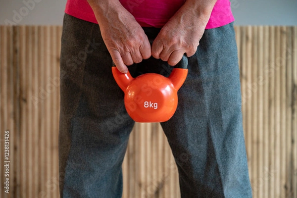 Obraz Hands holding an 8kg orange kettlebell