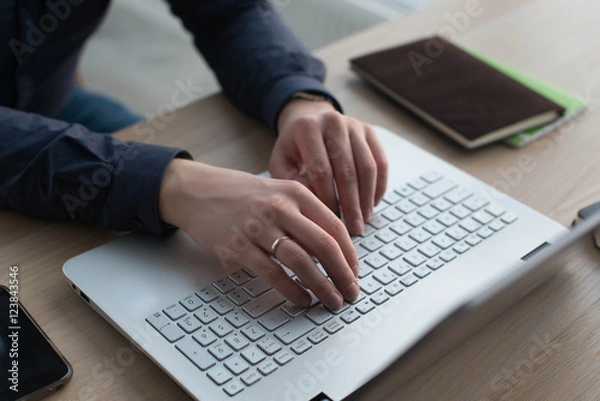 Fototapeta Hands typing on a laptop keyboard. A man works in an office at his workplace