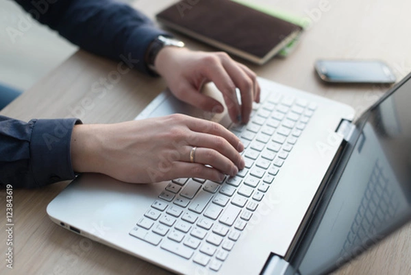 Fototapeta Hands typing on a laptop keyboard. A man works in an office at his workplace