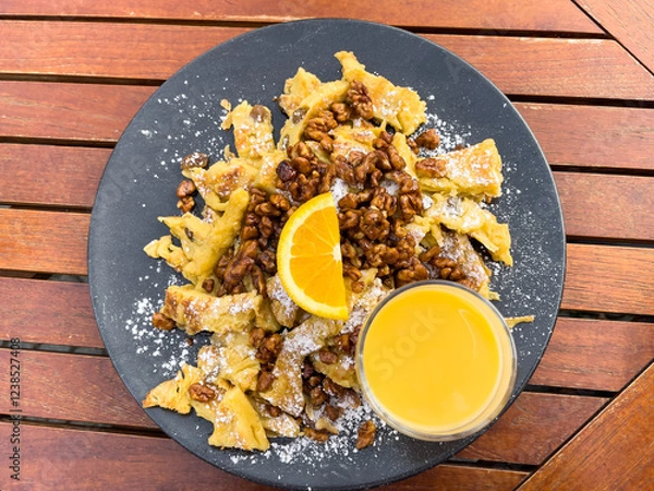 Fototapeta German strudel stuffed with walnuts, raisins, powdered sugar, orange slice on top and cream liquor glass. Scrambled pancake, classic sweet pie dessert concept