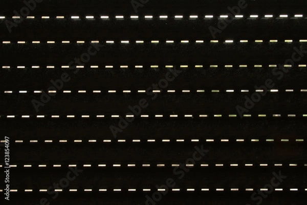 Fototapeta Small lit slits as seen from behind a window roller shutter, material texture