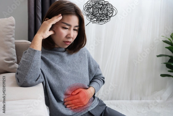 Obraz Asian woman suffering from nervous stomach, gut brain axis , feeling discomfort, pain ,connection between stress and digestive discomfort