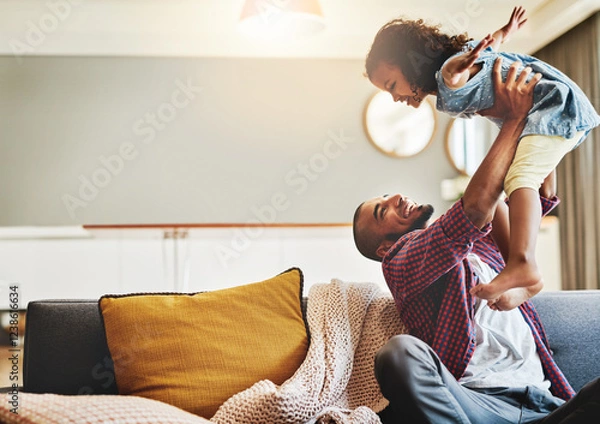 Fototapeta Dad, lift daughter and playing in home, love and parent support with flying adventure fantasy. Father, girl child and care for protection or security in living room, happy and games for bonding