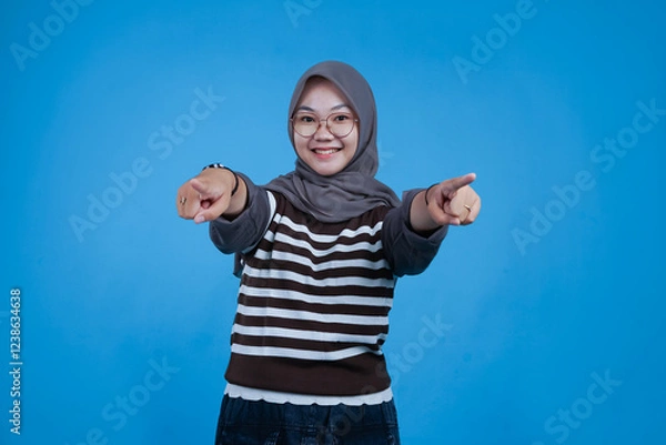 Fototapeta Happy Young Woman Pointing Both Hands Forward in a Blue Background