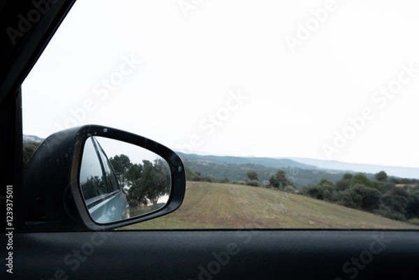 Fototapeta rear-view mirror and car part in nature landscape giving a holiday and road trip atmosphere