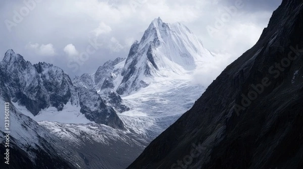 Fototapeta Majestic snow-capped mountains pierce a cloudy sky creating a dramatic landscape view