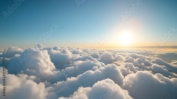Fototapeta Serene aerial view of fluffy clouds illuminated by the warm glow of a sunrise over the horizon
