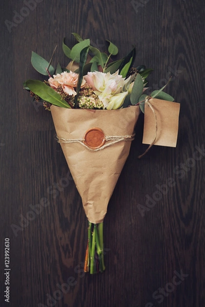 Obraz bouquet of flowers in the kraft paper on a dark wooden backgroun