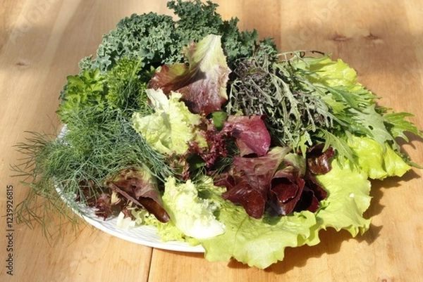 Obraz Fresh mixed salad greens on wooden table in natural light